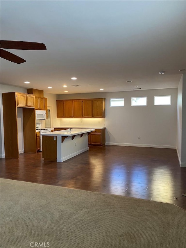 kitchen with white appliances, a kitchen breakfast bar, open floor plan, light countertops, and a center island