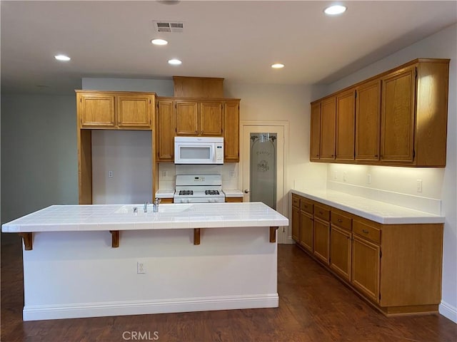 kitchen featuring tile counters, recessed lighting, white appliances, and brown cabinets