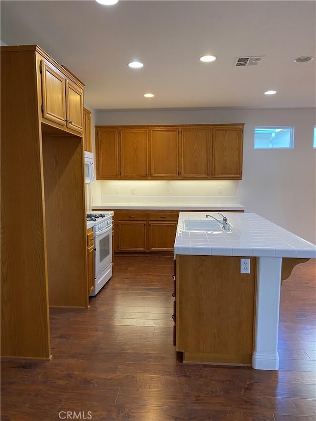 kitchen with white appliances, visible vents, dark wood finished floors, tile countertops, and a sink