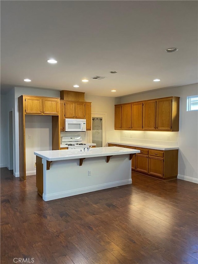 kitchen with dark wood-style floors, light countertops, white appliances, and brown cabinetry