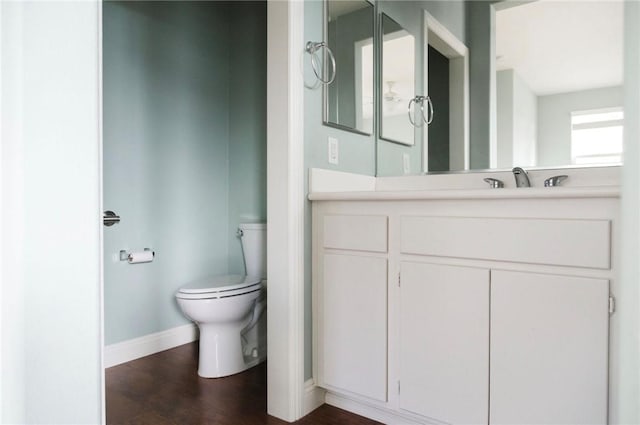 bathroom featuring baseboards, vanity, toilet, and wood finished floors