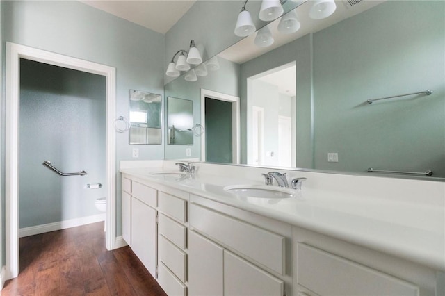 bathroom with double vanity, wood finished floors, a sink, and toilet