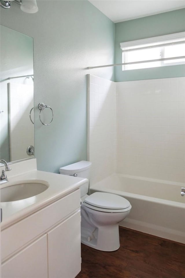 full bath with toilet, shower / bathtub combination, wood finished floors, and vanity