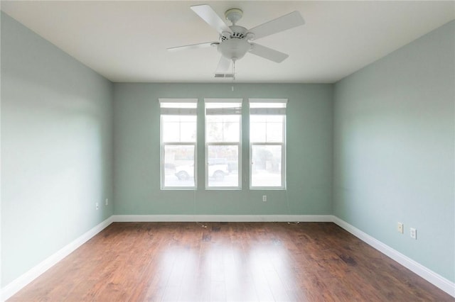 empty room with ceiling fan, wood finished floors, visible vents, and baseboards