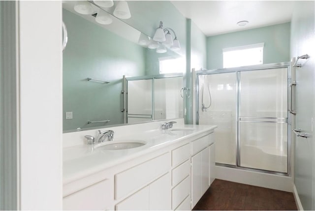 full bath featuring a sink, a shower stall, and wood finished floors