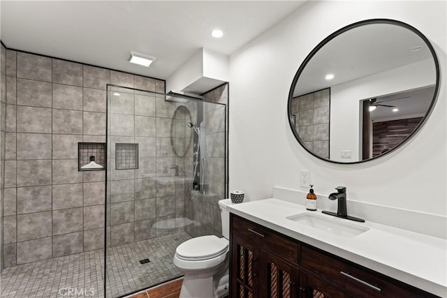 bathroom featuring tile patterned flooring, a tile shower, vanity, and toilet