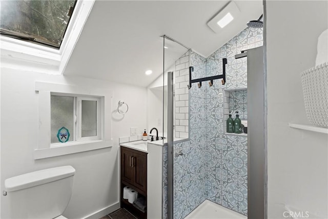 bathroom with a tile shower, vanity, toilet, and lofted ceiling