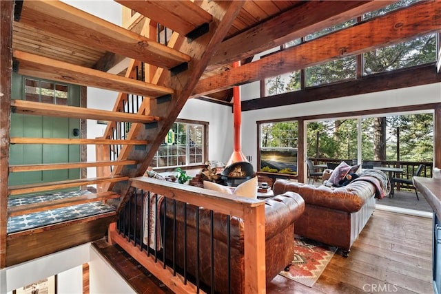 living room featuring a wood stove, beamed ceiling, wooden ceiling, and hardwood / wood-style flooring