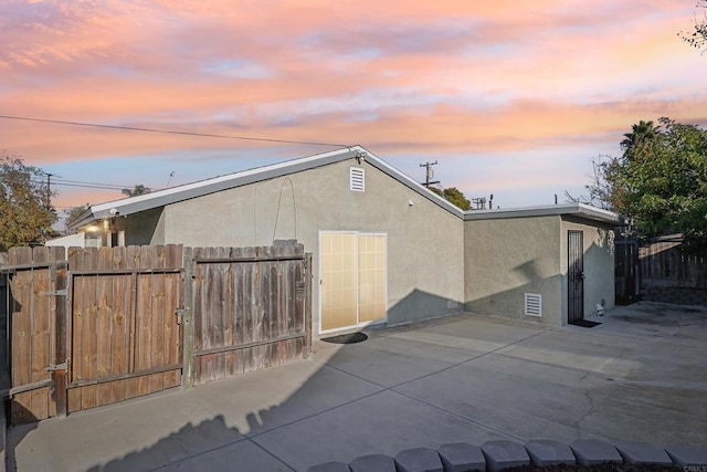 property exterior at dusk featuring a patio