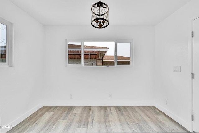 spare room with light hardwood / wood-style flooring and a notable chandelier