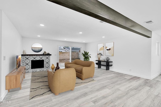 living room featuring a fireplace, beam ceiling, and light wood-type flooring