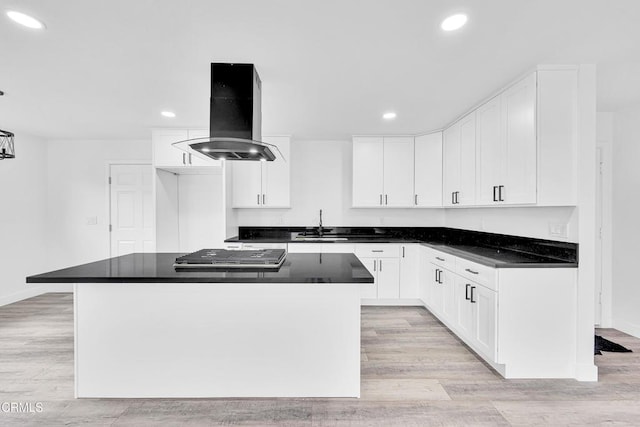 kitchen featuring island exhaust hood, a center island, white cabinets, and light hardwood / wood-style floors