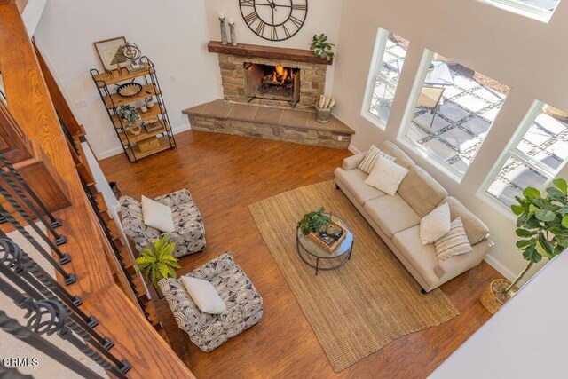 living room with hardwood / wood-style flooring, a stone fireplace, and plenty of natural light