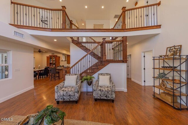 sitting room featuring a high ceiling, ceiling fan, and wood-type flooring