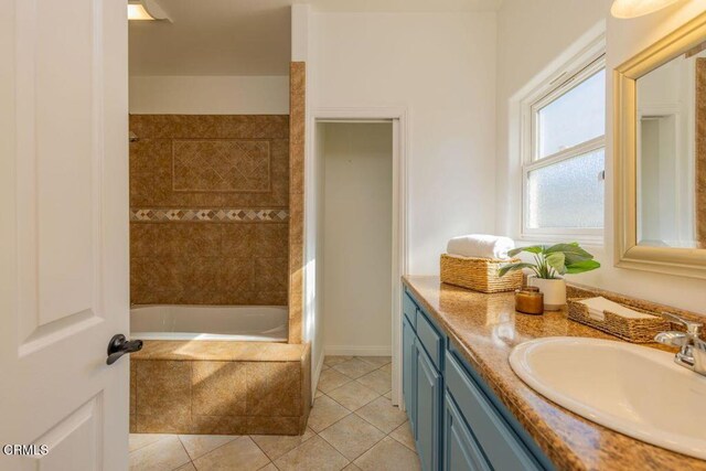 bathroom with tile patterned flooring, vanity, and tiled bath