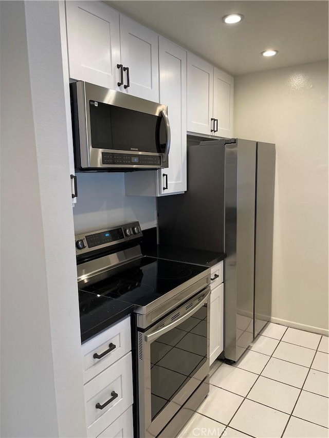 kitchen with appliances with stainless steel finishes, white cabinetry, and light tile patterned flooring