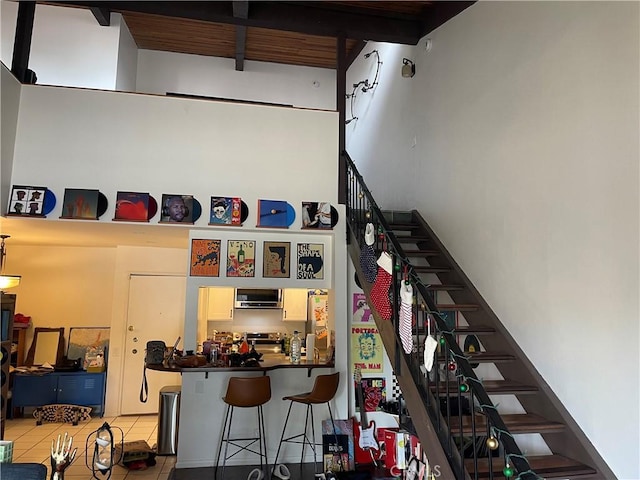 staircase featuring tile patterned flooring and beamed ceiling