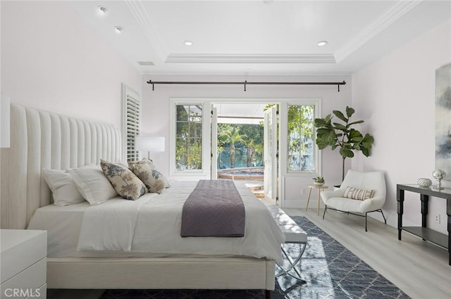 bedroom featuring a tray ceiling, crown molding, and light hardwood / wood-style floors