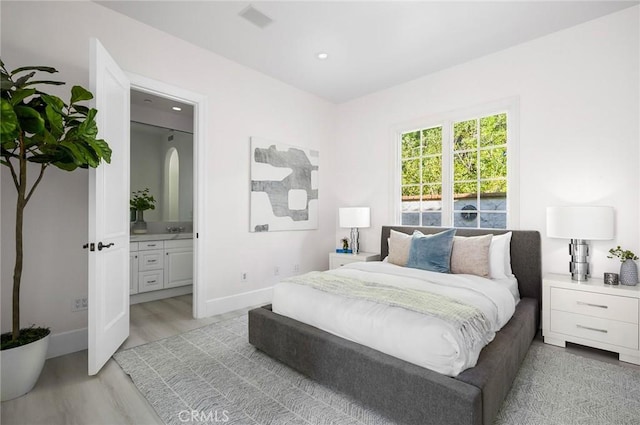 bedroom with connected bathroom, sink, and light hardwood / wood-style floors