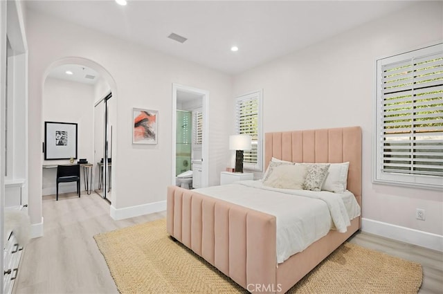 bedroom with ensuite bathroom and light hardwood / wood-style flooring