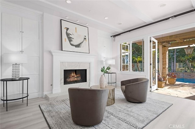 living room with beam ceiling, a high end fireplace, and light hardwood / wood-style flooring