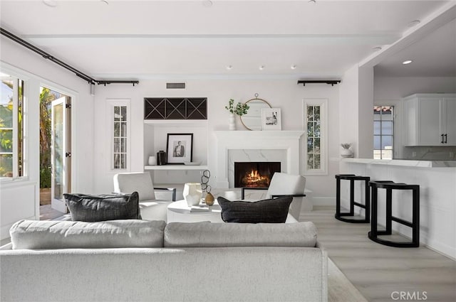 living room featuring light wood-type flooring and a high end fireplace