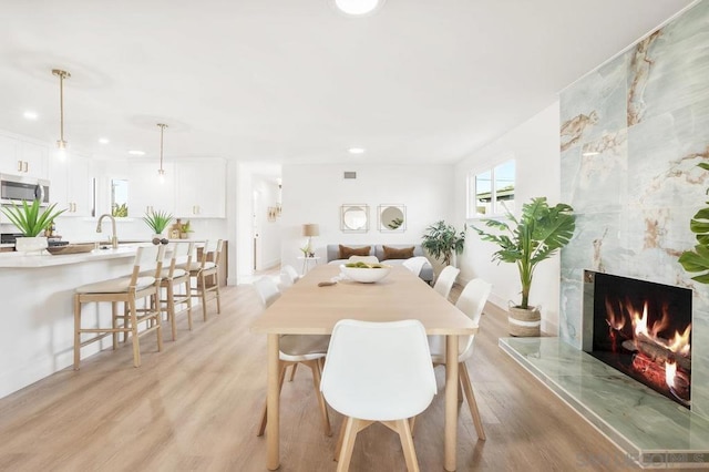 dining area with sink, light hardwood / wood-style flooring, and a premium fireplace