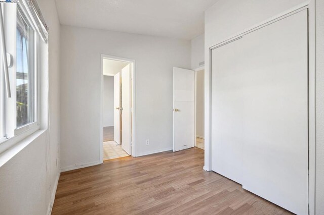 unfurnished bedroom featuring a closet, light hardwood / wood-style flooring, and lofted ceiling