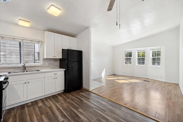 kitchen featuring ceiling fan, sink, dark hardwood / wood-style floors, black refrigerator, and white cabinets