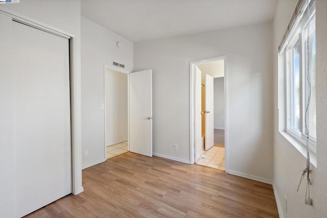 unfurnished bedroom with a closet and light wood-type flooring