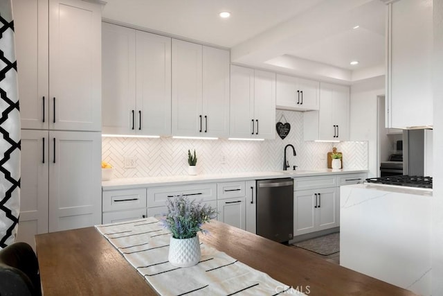 kitchen featuring decorative backsplash, dishwasher, white cabinets, and sink