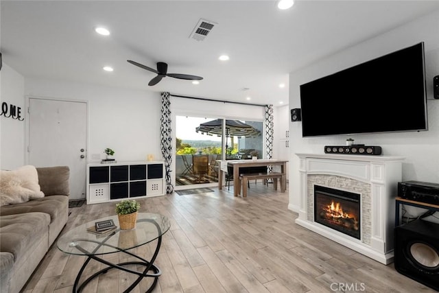 living room with ceiling fan, a fireplace, and light wood-type flooring