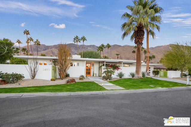 single story home featuring a mountain view and a front lawn