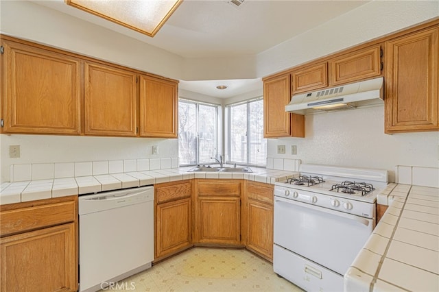 kitchen with white appliances, tile countertops, and sink