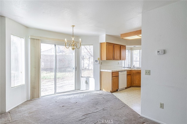 kitchen featuring decorative light fixtures, white dishwasher, an inviting chandelier, and a wealth of natural light