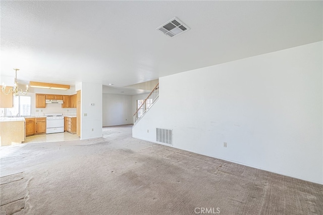 unfurnished living room with light carpet and an inviting chandelier