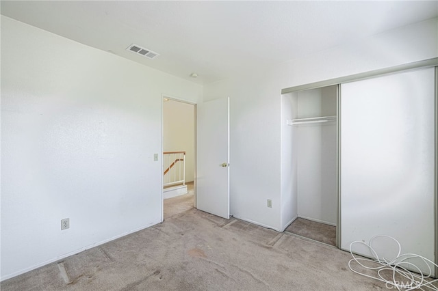 unfurnished bedroom with a closet and light colored carpet