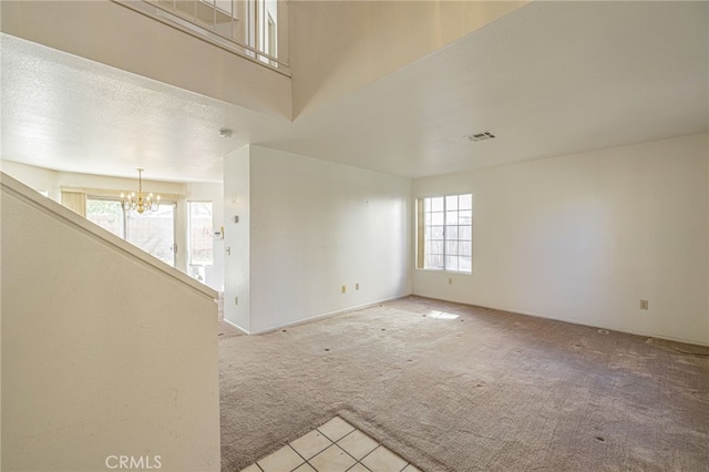 unfurnished living room featuring light carpet, plenty of natural light, a textured ceiling, and an inviting chandelier