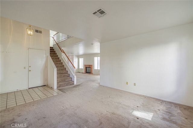 interior space featuring a fireplace, light colored carpet, and a notable chandelier