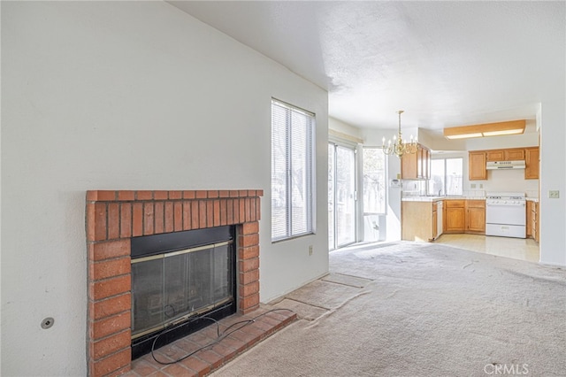 unfurnished living room with a chandelier, light colored carpet, and a brick fireplace