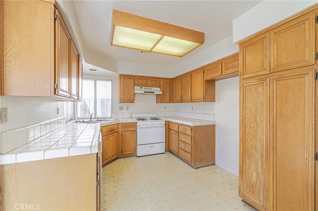 kitchen with white range oven, tile counters, and sink