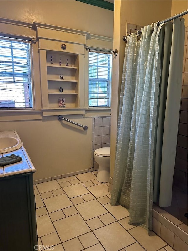 bathroom with a shower with curtain, a wealth of natural light, tile patterned flooring, and vanity