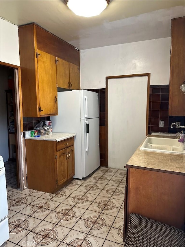 kitchen with decorative backsplash, white appliances, sink, and light tile patterned floors