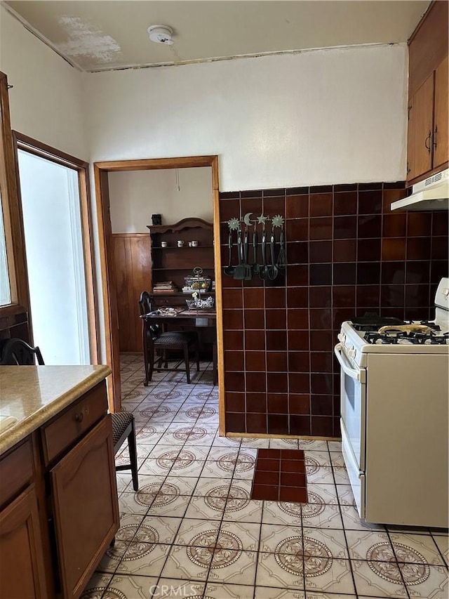 kitchen featuring gas range gas stove, light tile patterned flooring, and tile walls