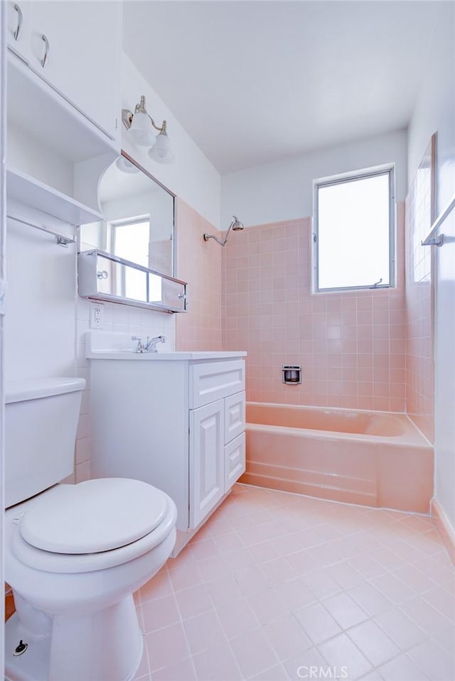 full bathroom featuring vanity, toilet, tiled shower / bath, and a healthy amount of sunlight