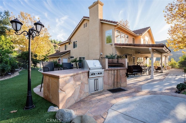 view of patio with ceiling fan, exterior kitchen, exterior bar, and grilling area