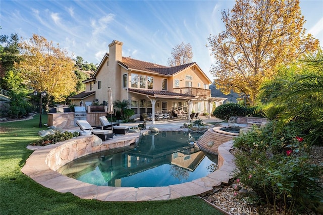 back of house with a balcony, area for grilling, a patio area, and a pool with hot tub