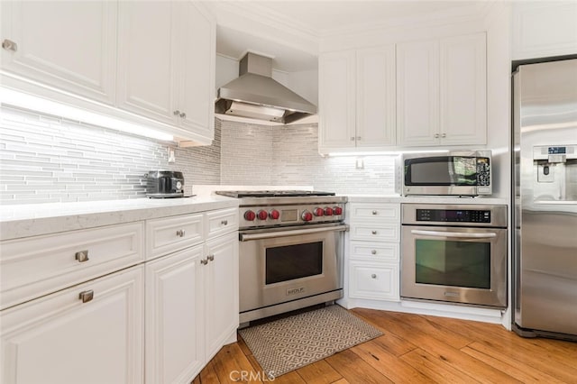 kitchen featuring light hardwood / wood-style floors, wall chimney range hood, stainless steel appliances, and white cabinetry