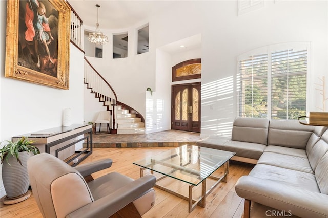 living room featuring a chandelier, french doors, wood-type flooring, and a high ceiling