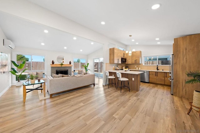 living room with a wall unit AC, plenty of natural light, vaulted ceiling, and light wood-type flooring